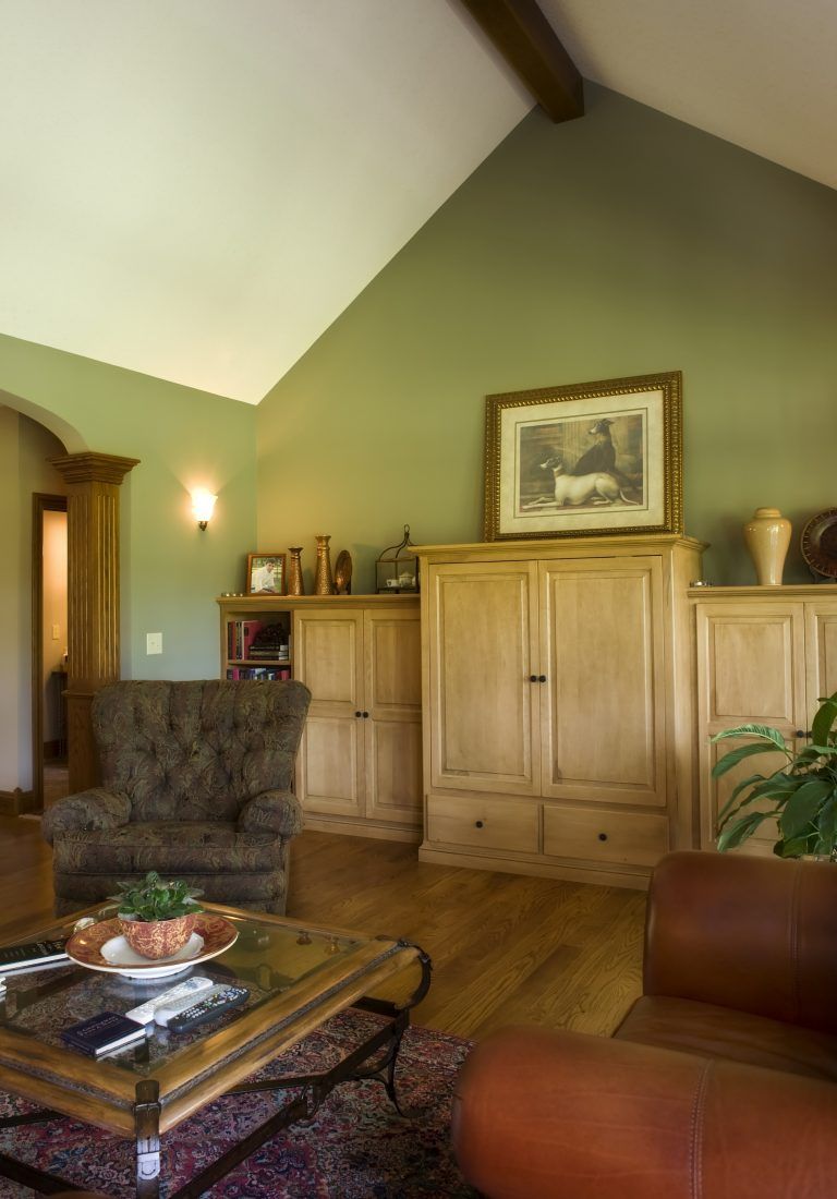 A living room with green walls and a vaulted ceiling.