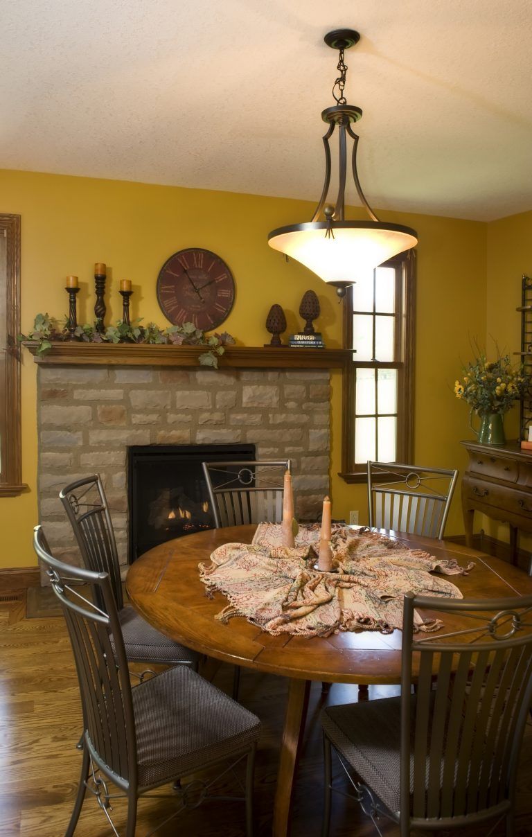 A dining room with a table and chairs and a fireplace.