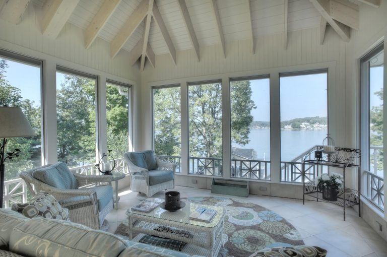 A living room with a lot of windows overlooking a lake.