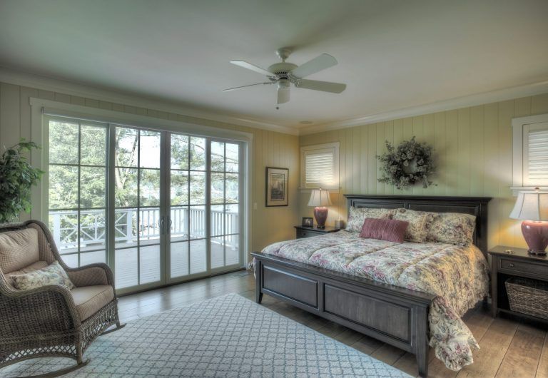 A bedroom with a king size bed , sliding glass doors and a ceiling fan.