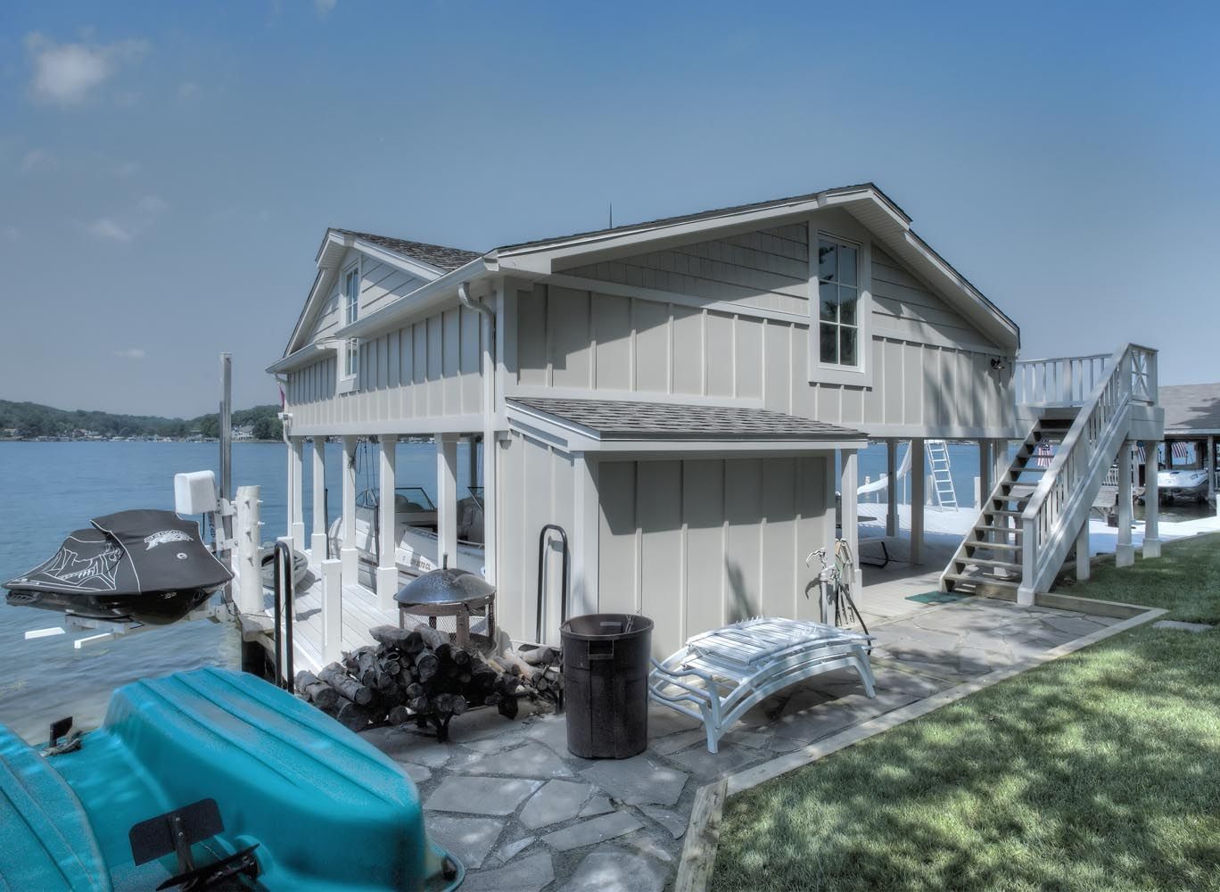 A house with stairs leading up to it is next to a body of water.