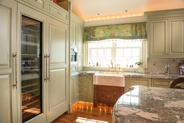 A kitchen with white cabinets, granite counter tops, and a wine cooler.