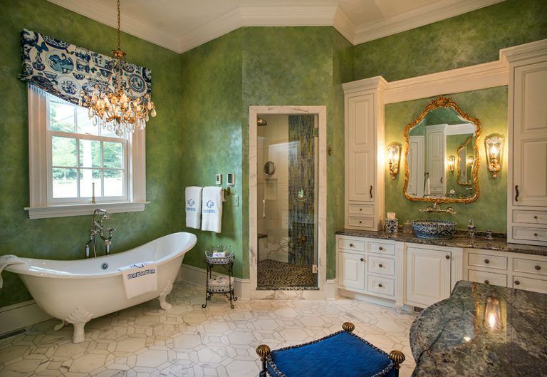A bathroom with green walls, a claw foot tub, a sink , and a mirror.