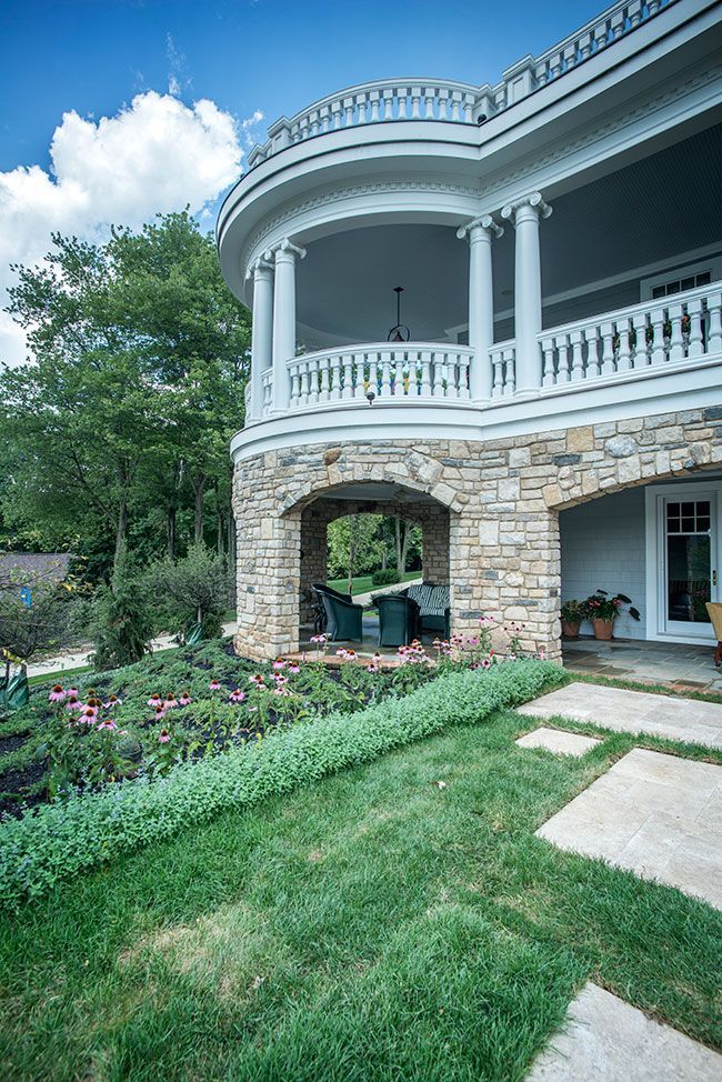 A large house with a large porch and a stone walkway leading to it.