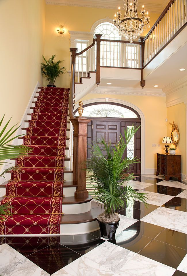 A staircase with a red carpet and a black and white checkered floor.