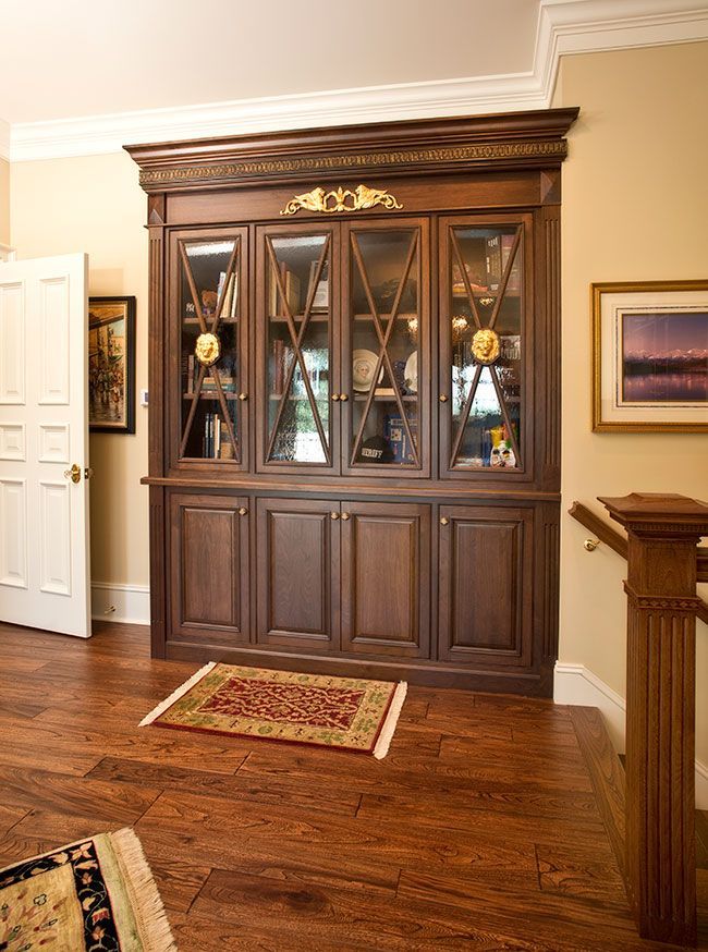A living room with a bookcase and a rug on the floor.