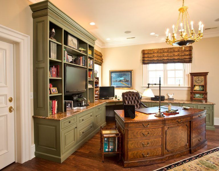 A home office with a desk a chair and a television.