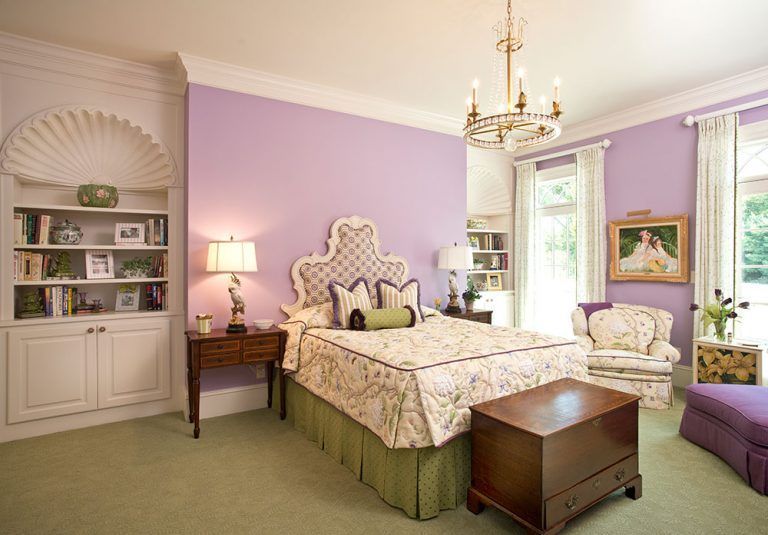 A bedroom with purple walls and a large bed.