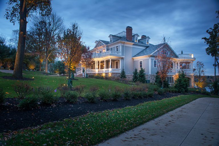 A large white house is sitting on top of a lush green hill.