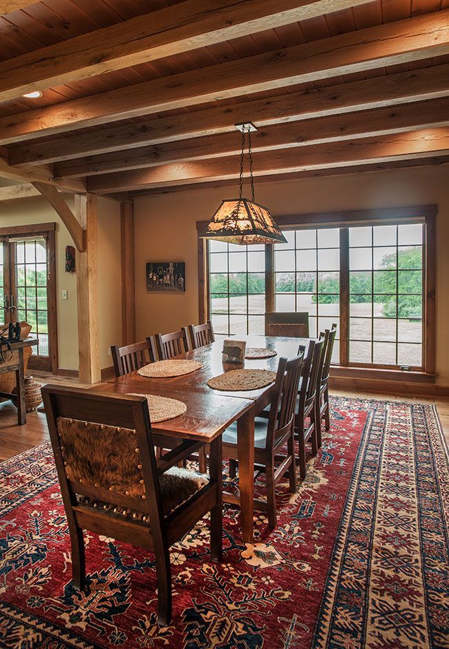 A dining room with a long table and chairs and a rug.