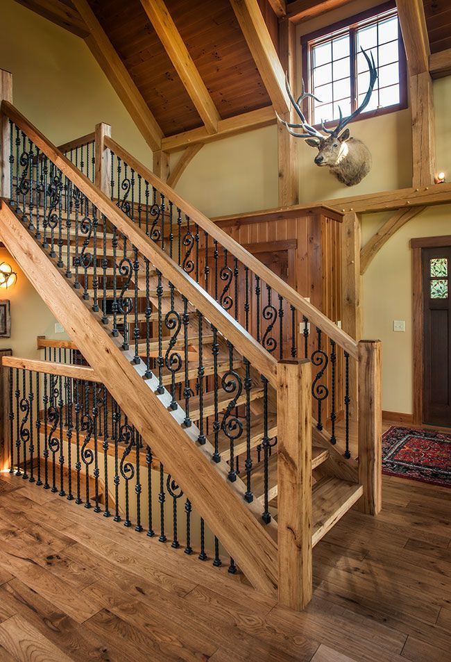 A wooden staircase with wrought iron railings and a deer head on the wall.