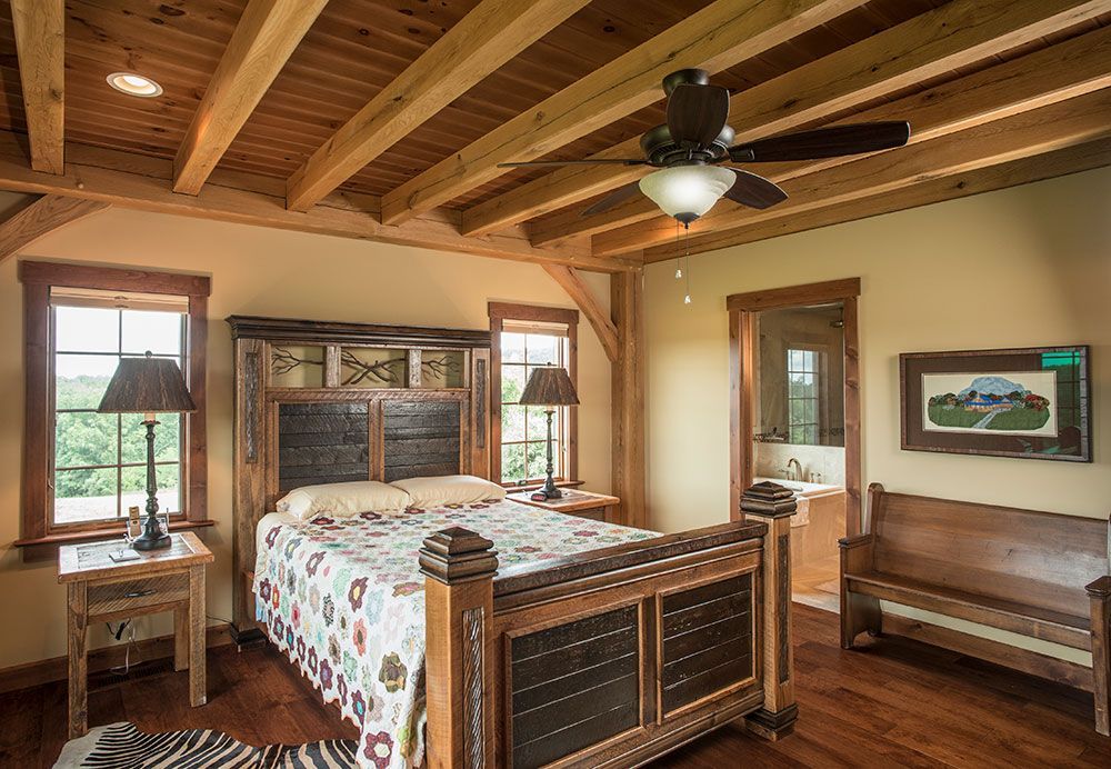 A bedroom with a bed , bench , lamps and a ceiling fan.