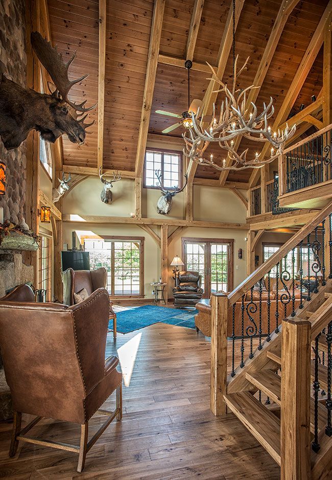 A living room with a moose head on the wall and stairs leading up to the second floor.
