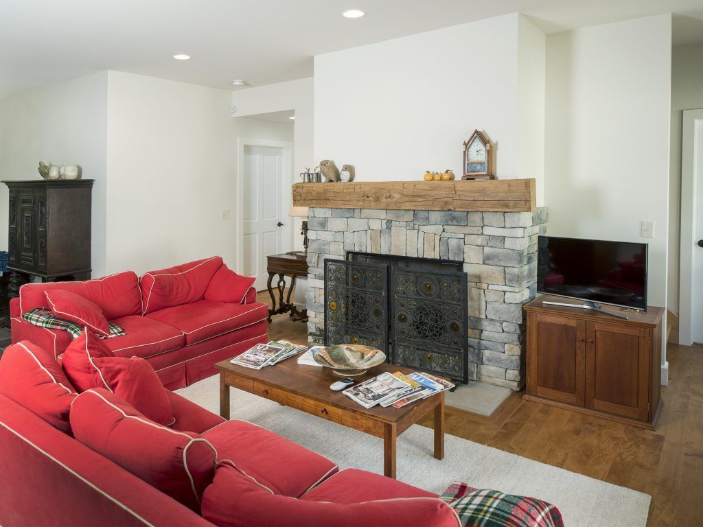 A living room with a red couch and a fireplace.