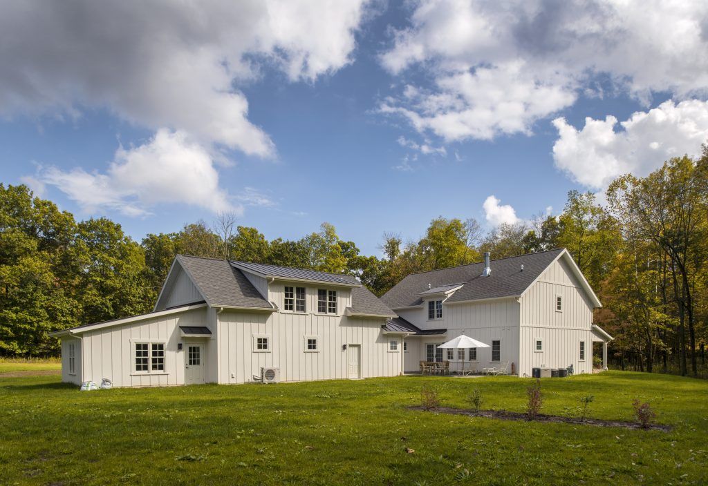 A large white house is sitting on top of a lush green field.