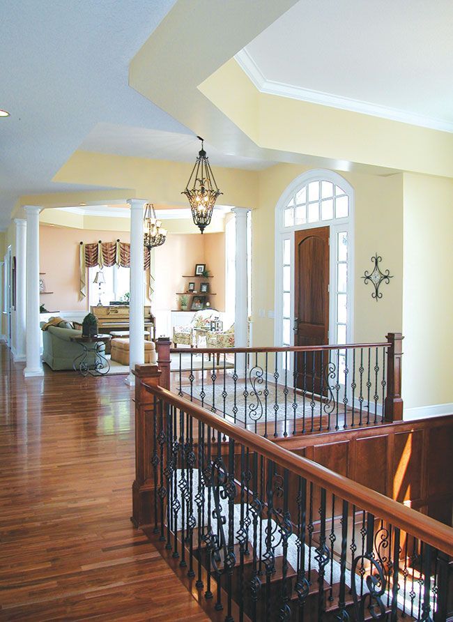 A staircase with a wrought iron railing leading up to a living room.