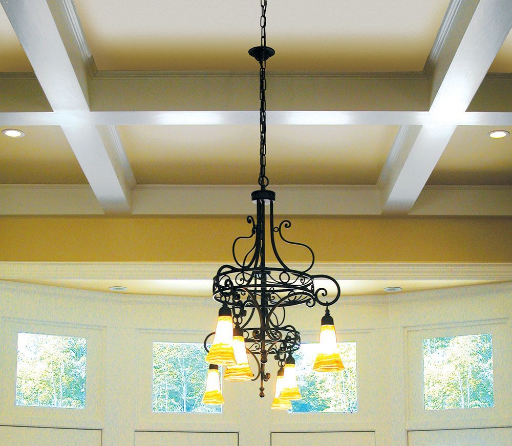 A chandelier is hanging from the ceiling of a room with windows.
