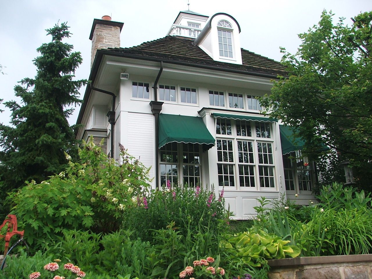 A white house with a green awning on the windows.
