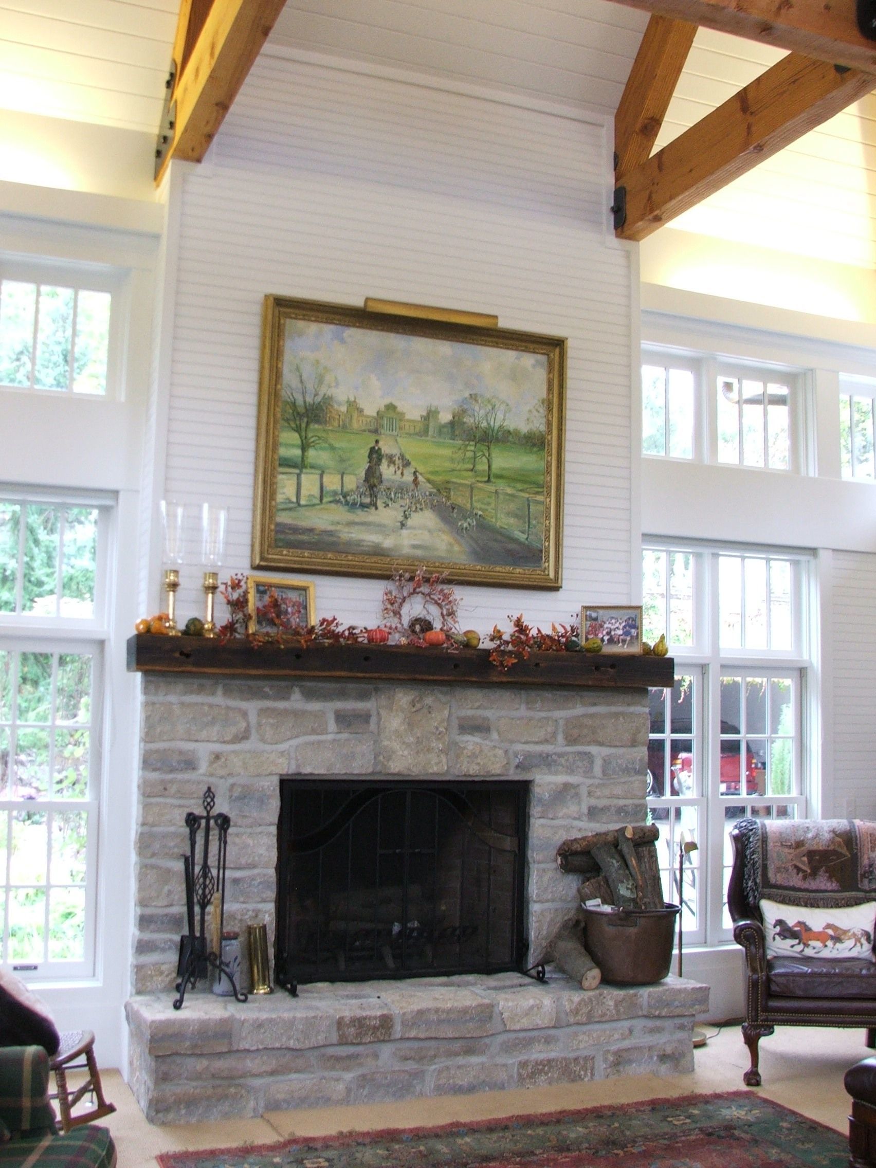 A living room with a fireplace and a painting on the mantle.