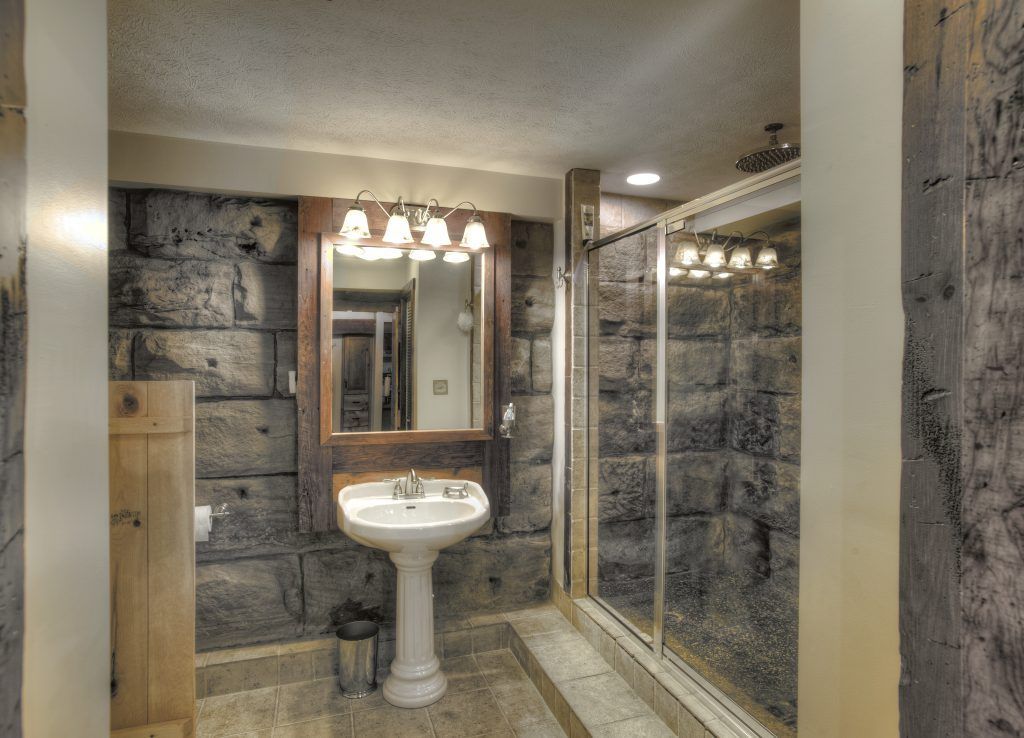 A bathroom with a sink, mirror, and a walk in shower.