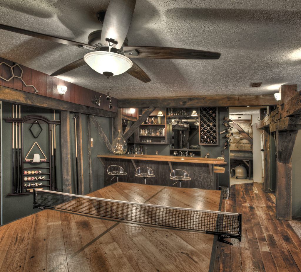 A room with a ping pong table and a ceiling fan.