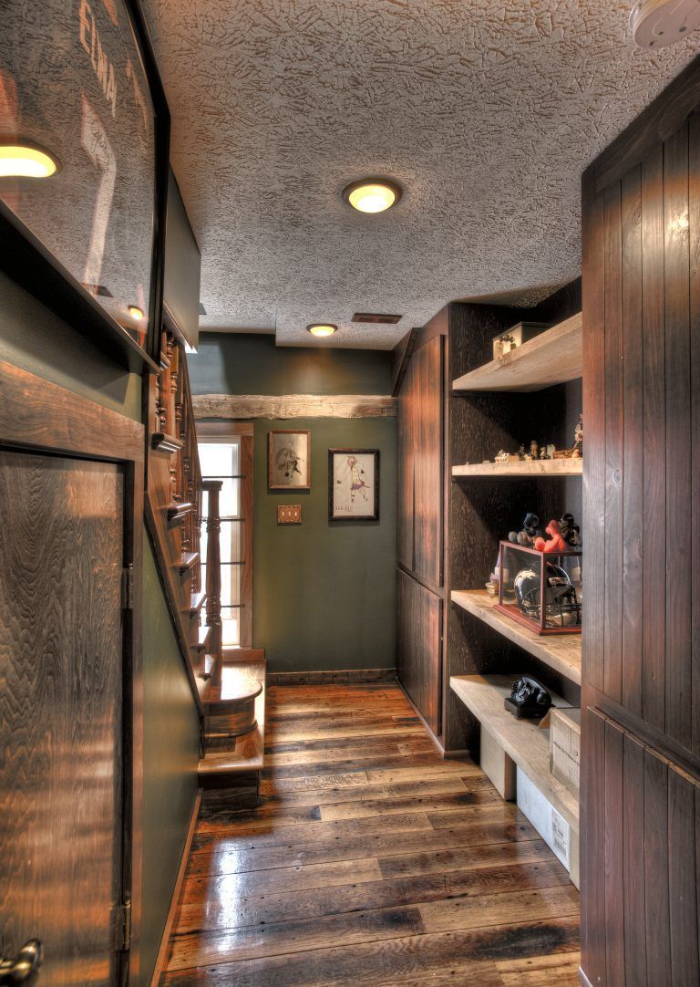A hallway with wooden floors and shelves in a house.