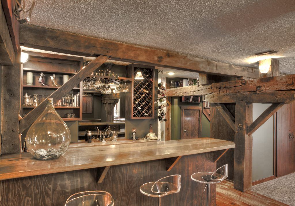 A bar in a basement with stools and a wine rack.