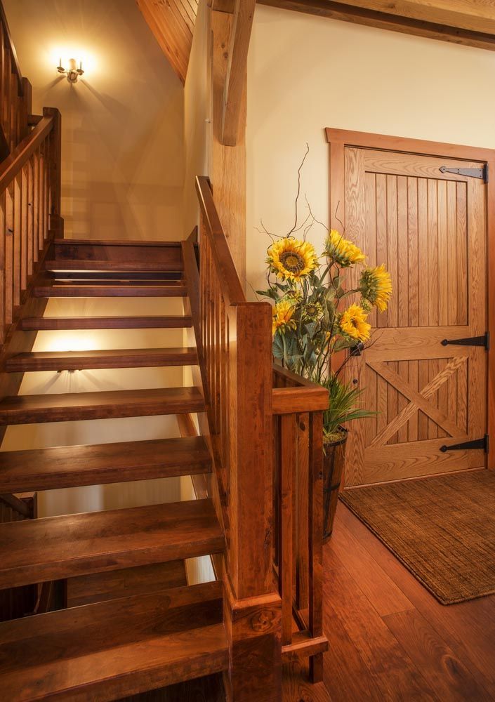 A wooden staircase with a vase of sunflowers on the railing.