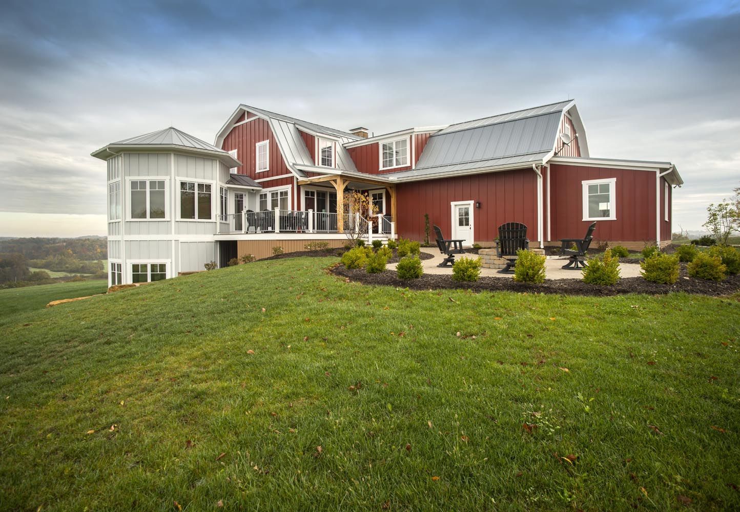 A large red and white house is sitting on top of a grassy hill.