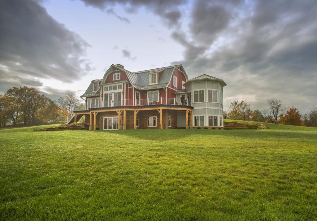 A large house is sitting in the middle of a lush green field.