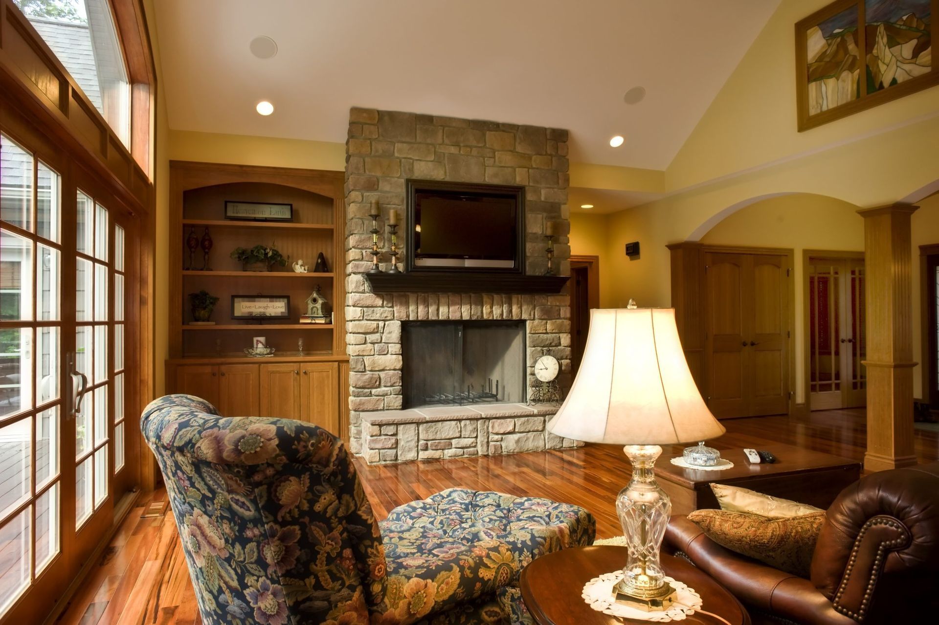 A living room with a fireplace and chairs and a lamp.