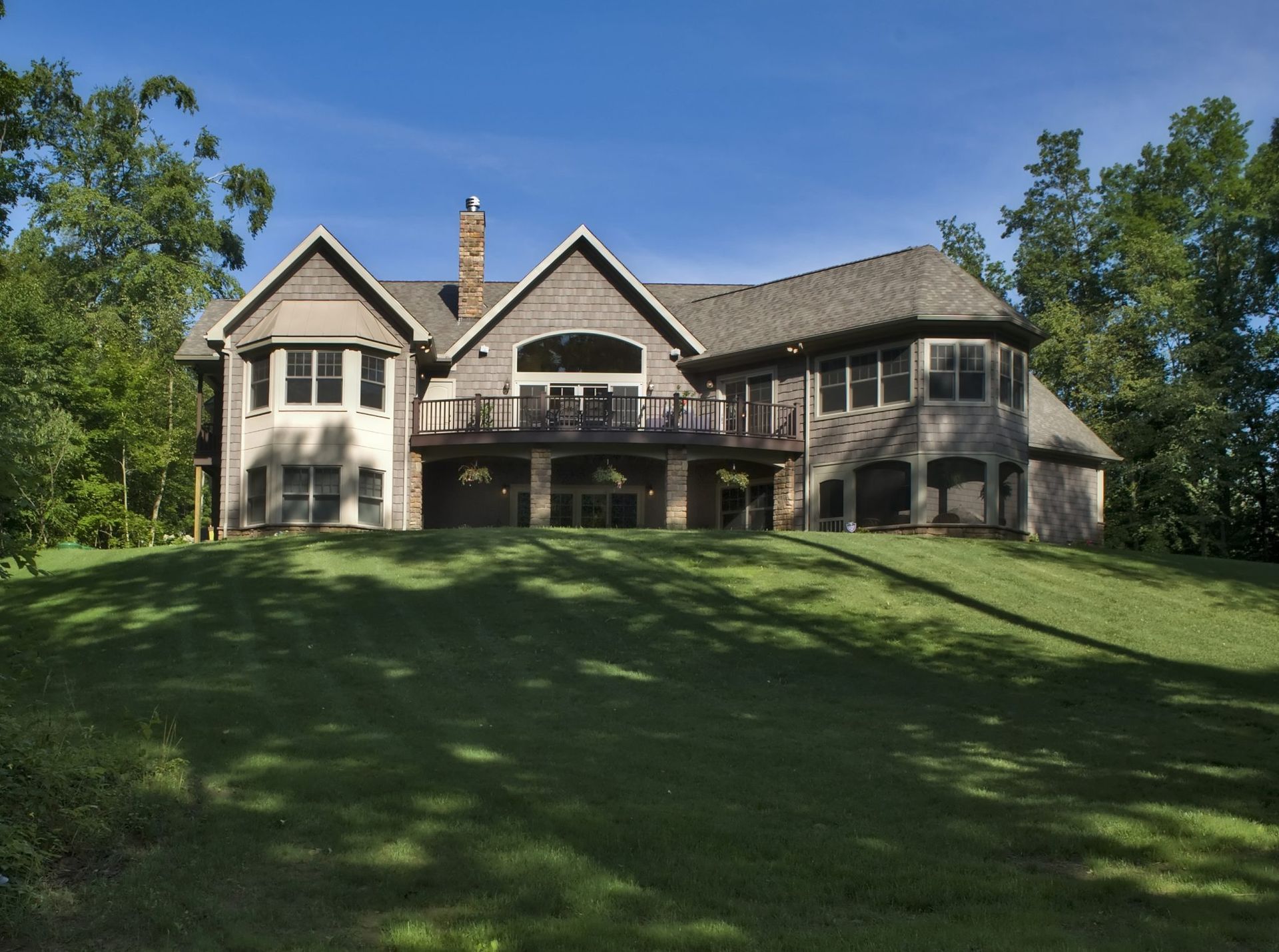 A large house sits on top of a lush green hillside.