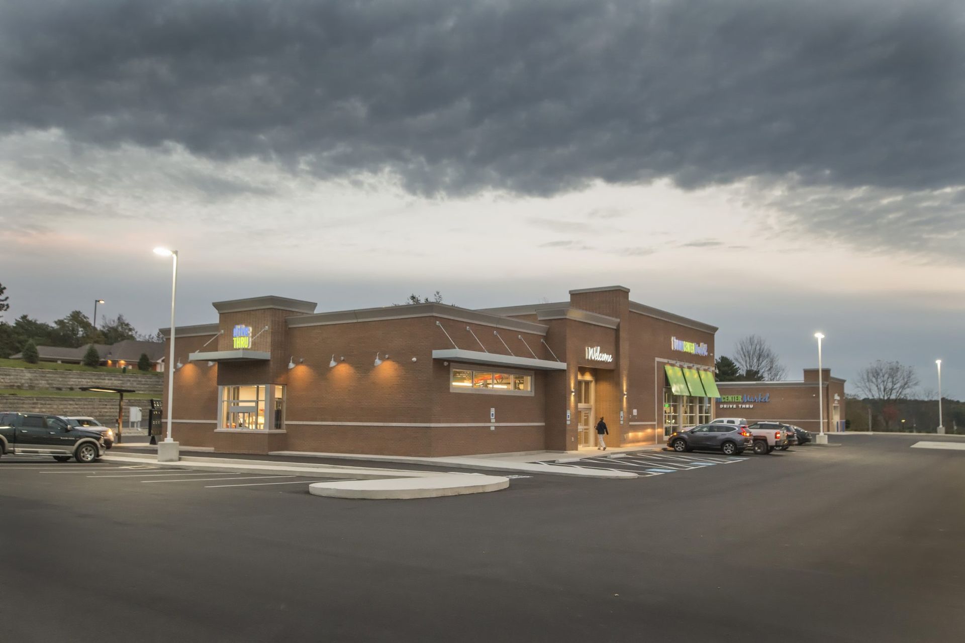 A brick building with cars parked in front of it on a cloudy day.