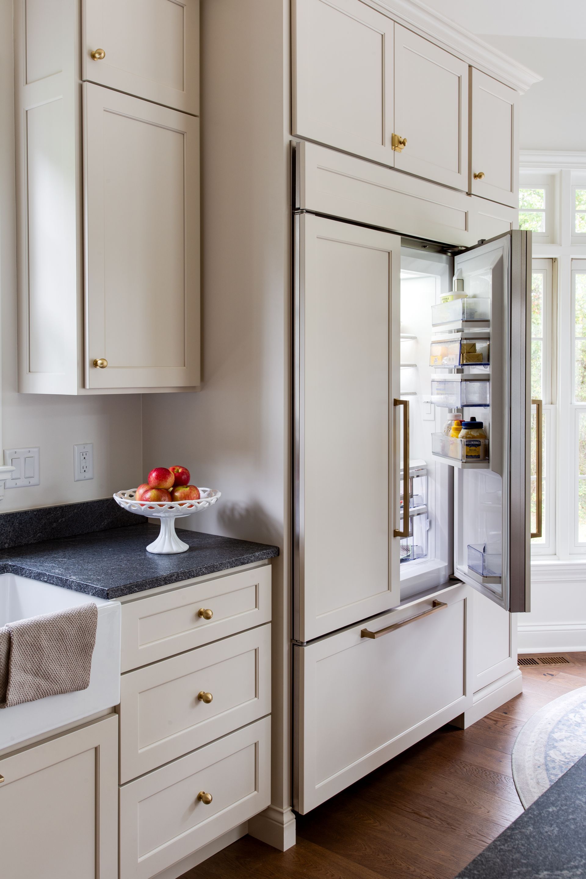 A kitchen with white cabinets and a refrigerator with the door open.