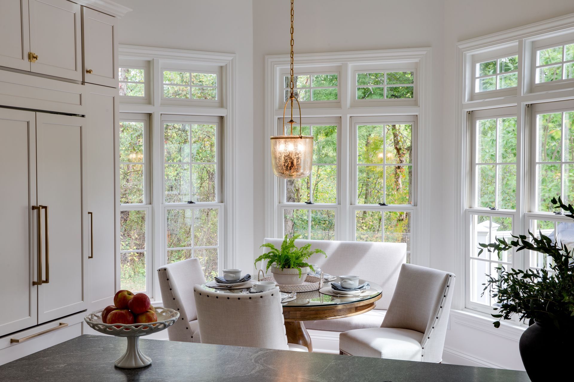 A dining room with a table and chairs and lots of windows.