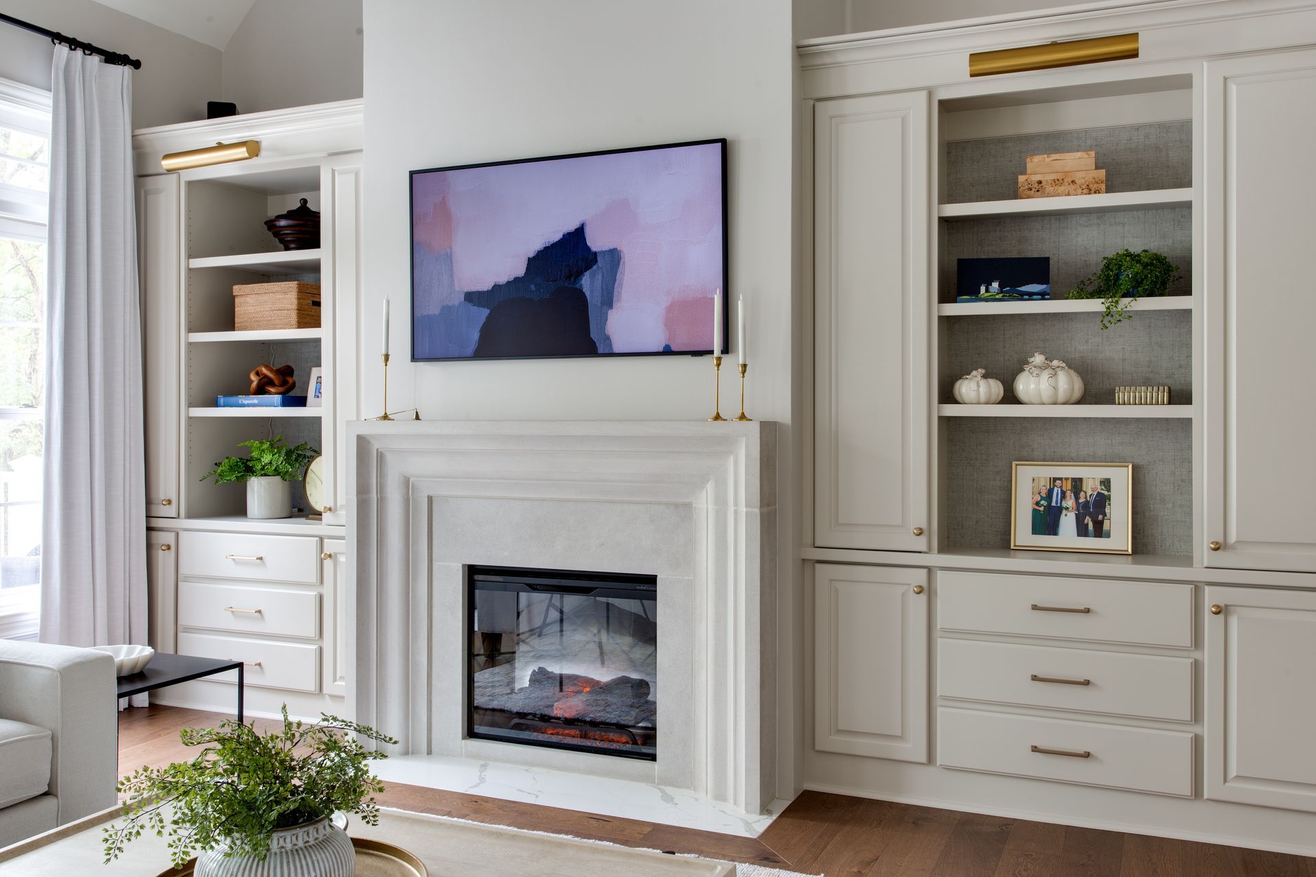 A living room with a fireplace and a flat screen tv on the wall.