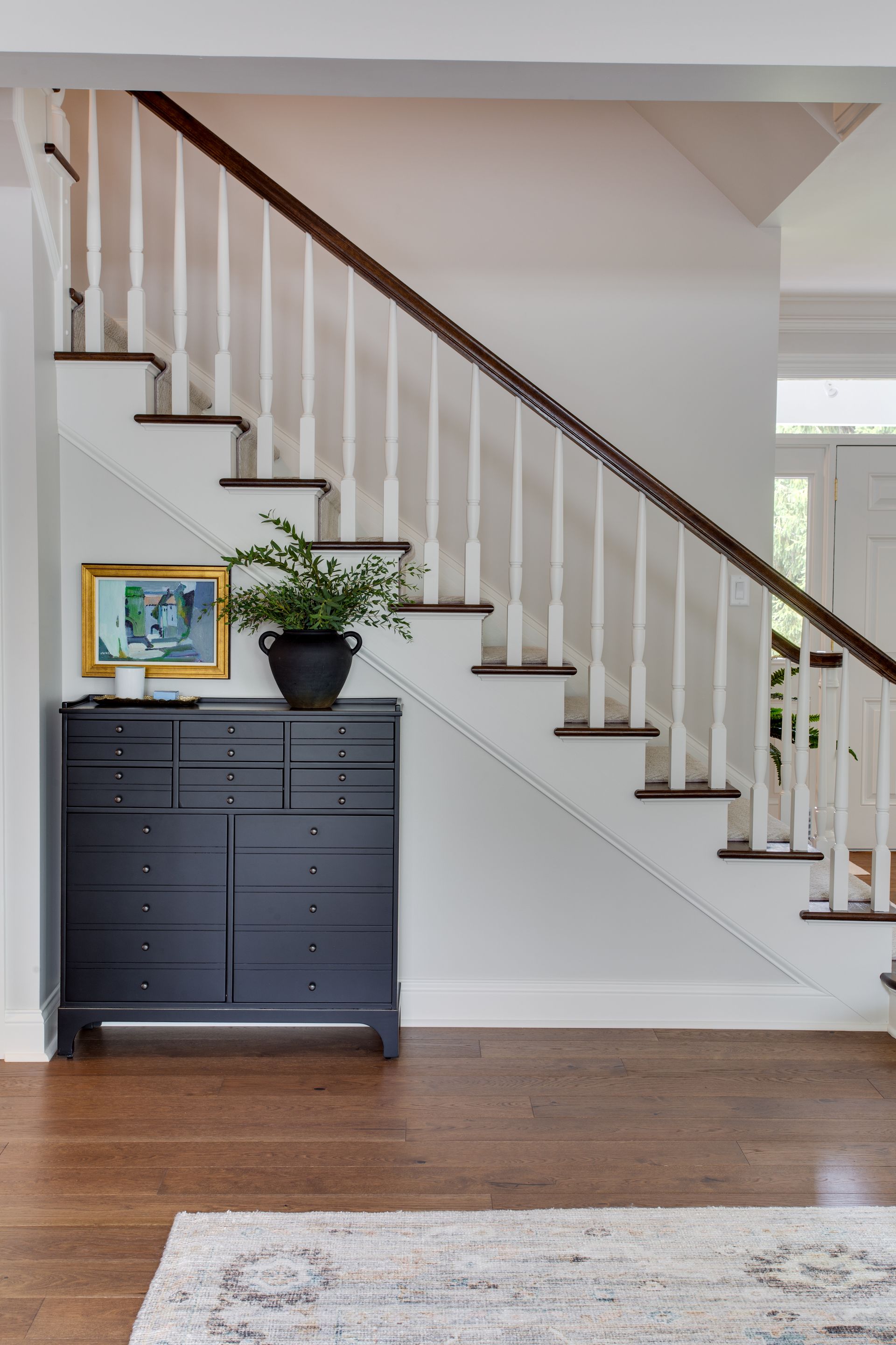 A staircase in a house with a dresser underneath it.
