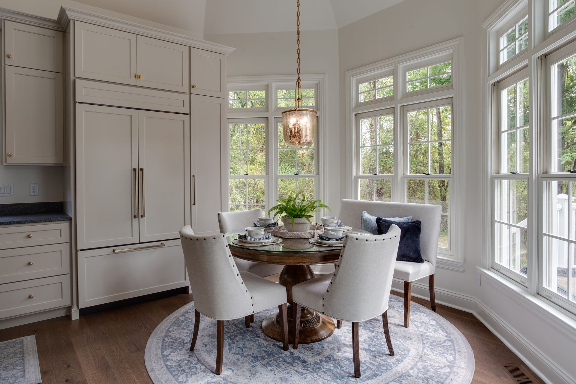A dining room with a table and chairs and lots of windows.
