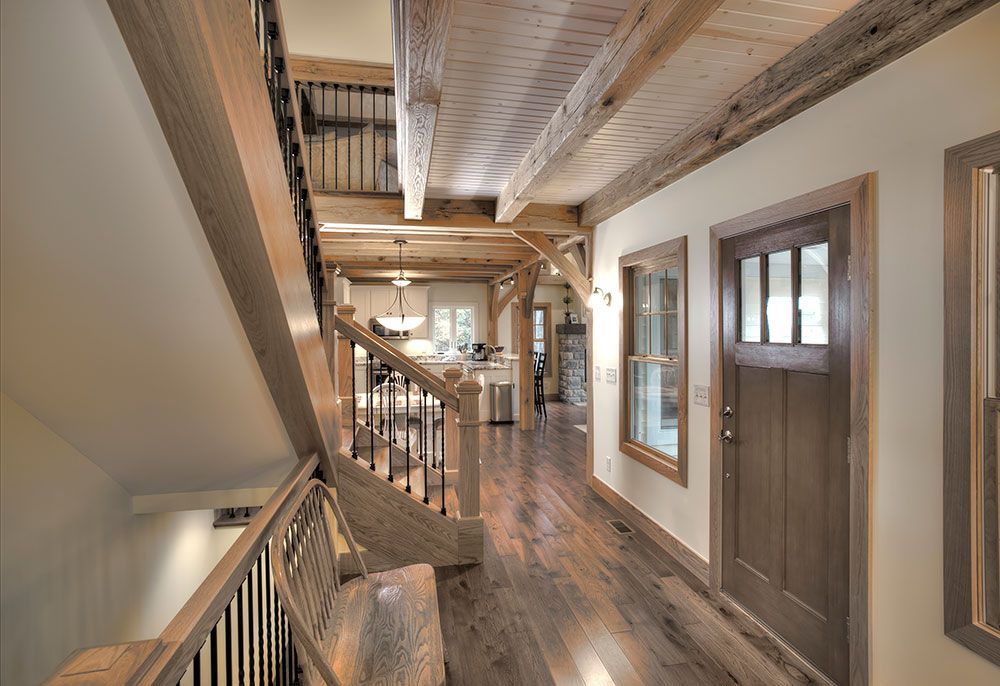 A long hallway with wooden floors and stairs in a house.
