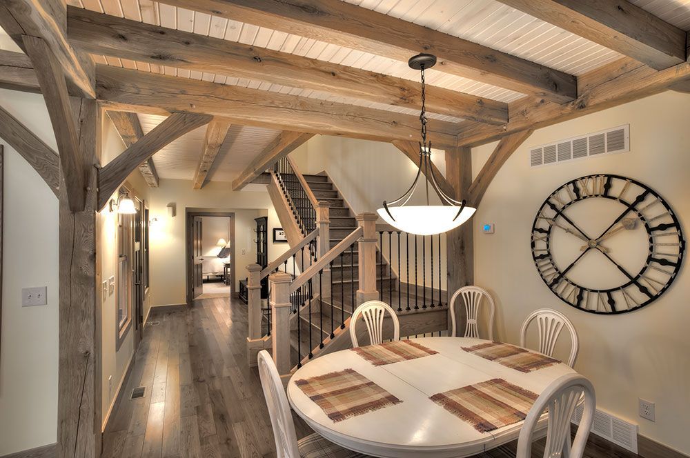 A dining room with a table and chairs and a clock on the wall.