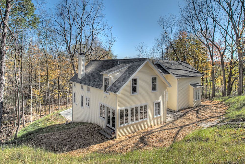 A white house is sitting on top of a hill in the middle of a forest.