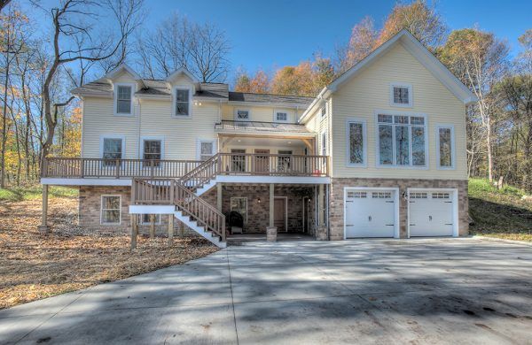 A large white house with two garages and a deck.