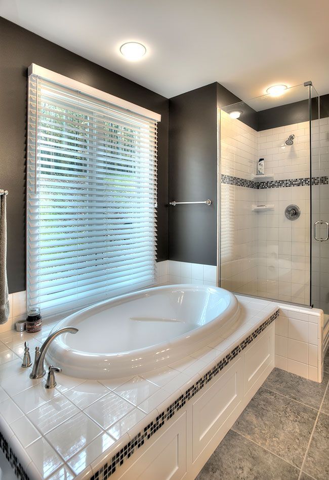 A bathroom with a tub, shower and window.