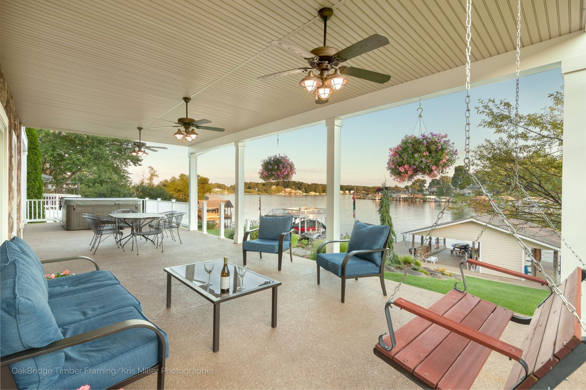 A porch with chairs, a swing, and a ceiling fan.