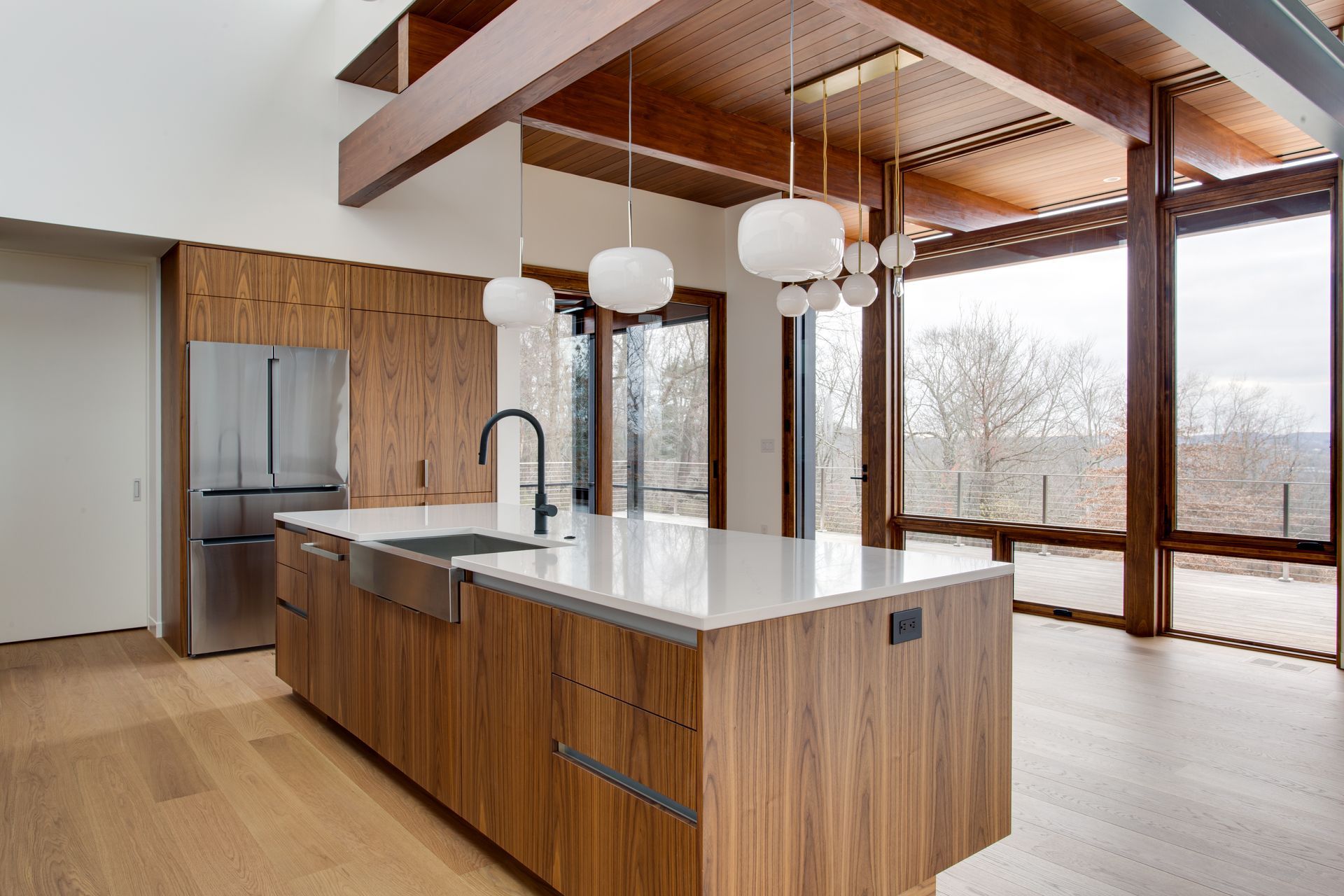 Modern kitchen with wood island, stainless steel appliances, and large windows overlooking trees