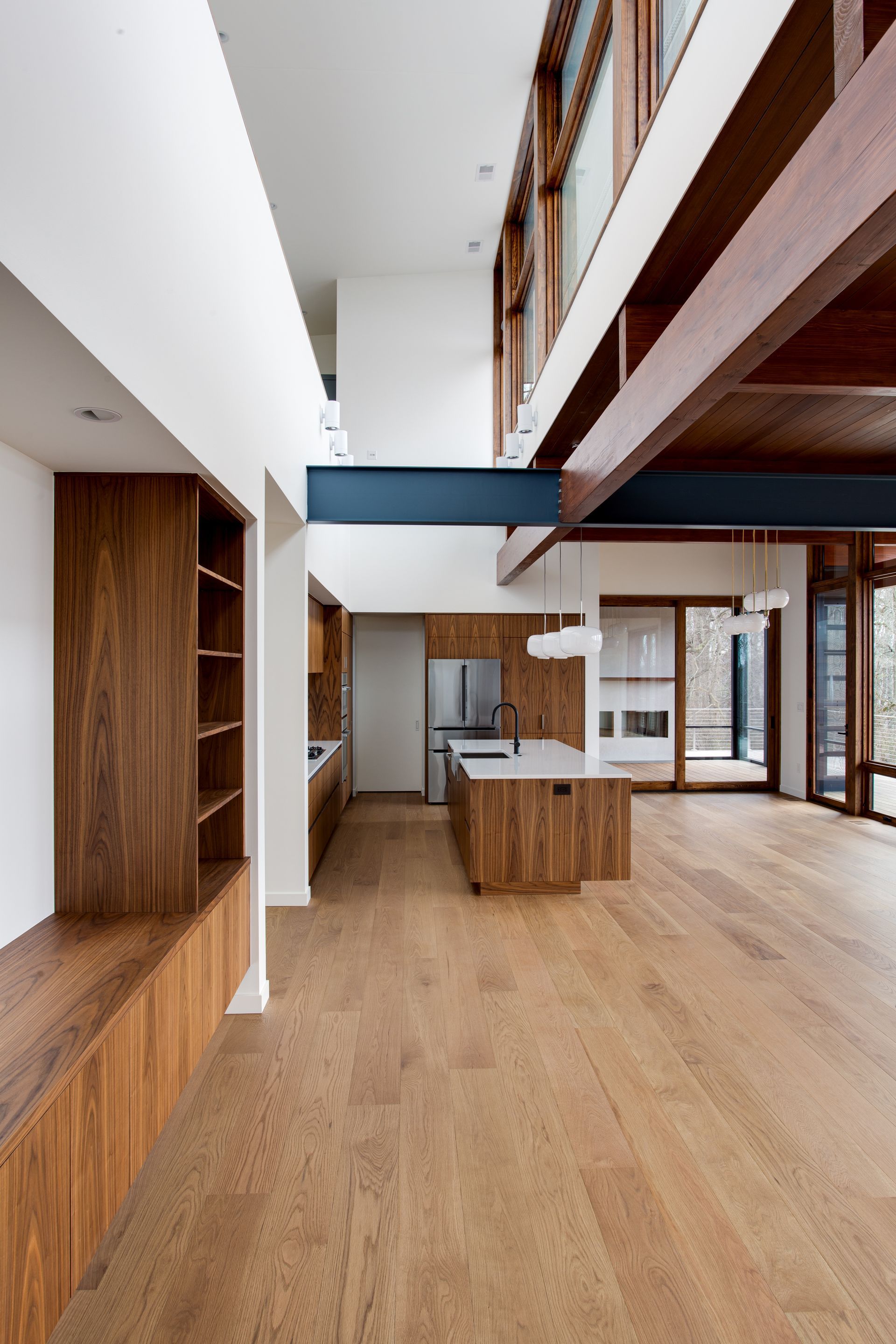Modern open-concept room with wood floors, exposed beams, and a central kitchen island