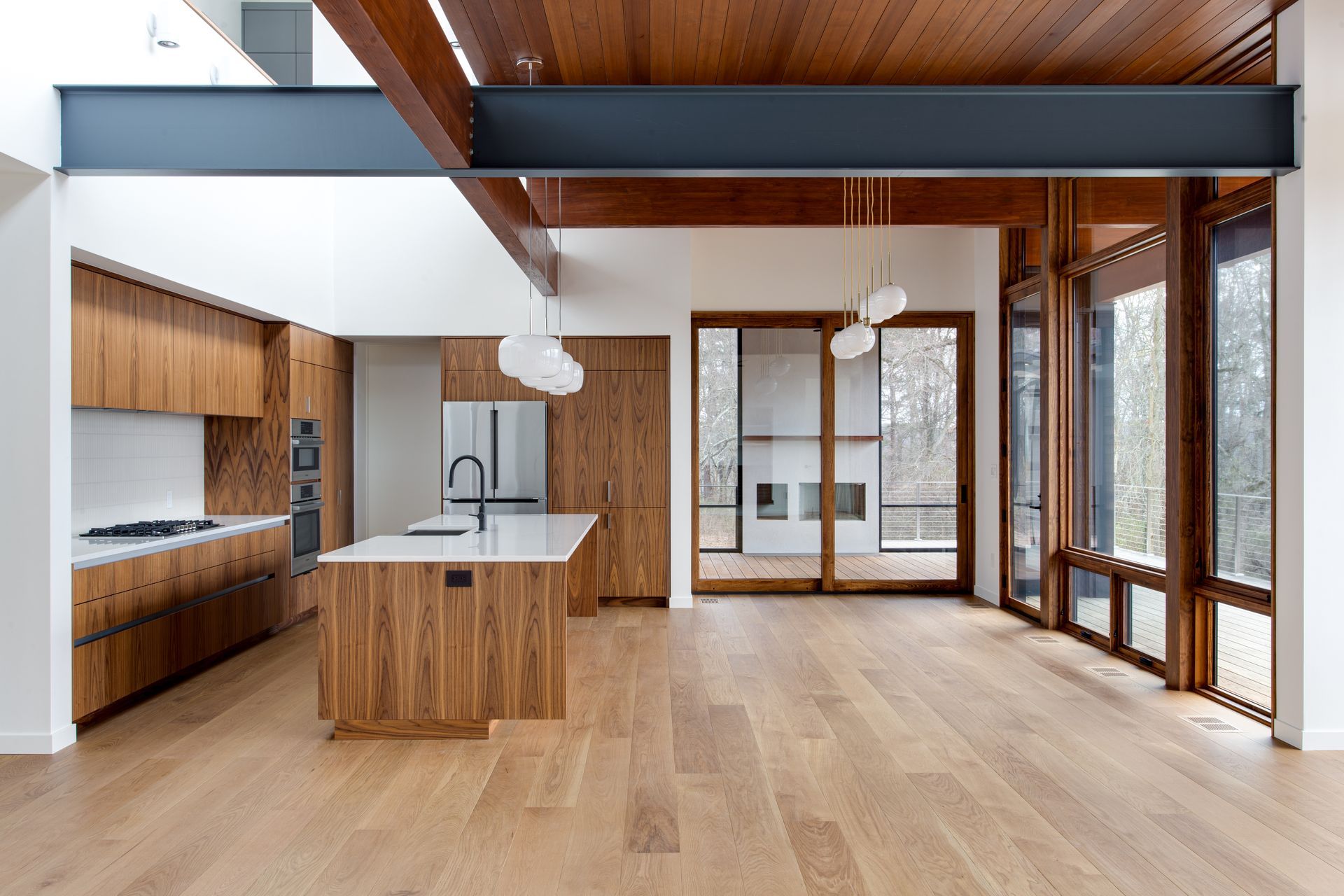Modern open-plan kitchen and living space with wood ceilings, island, and large windows