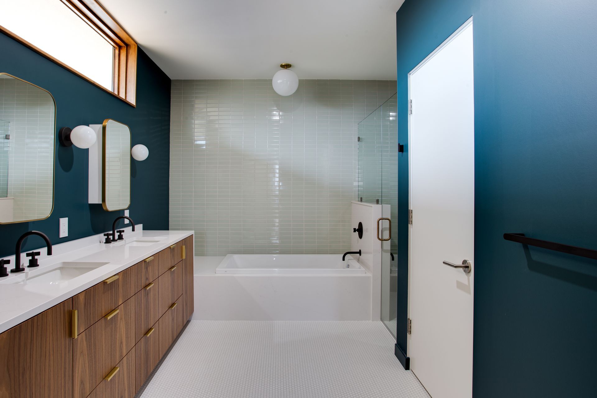 Modern bathroom with teal walls, double vanity, bathtub, and white tiled floor