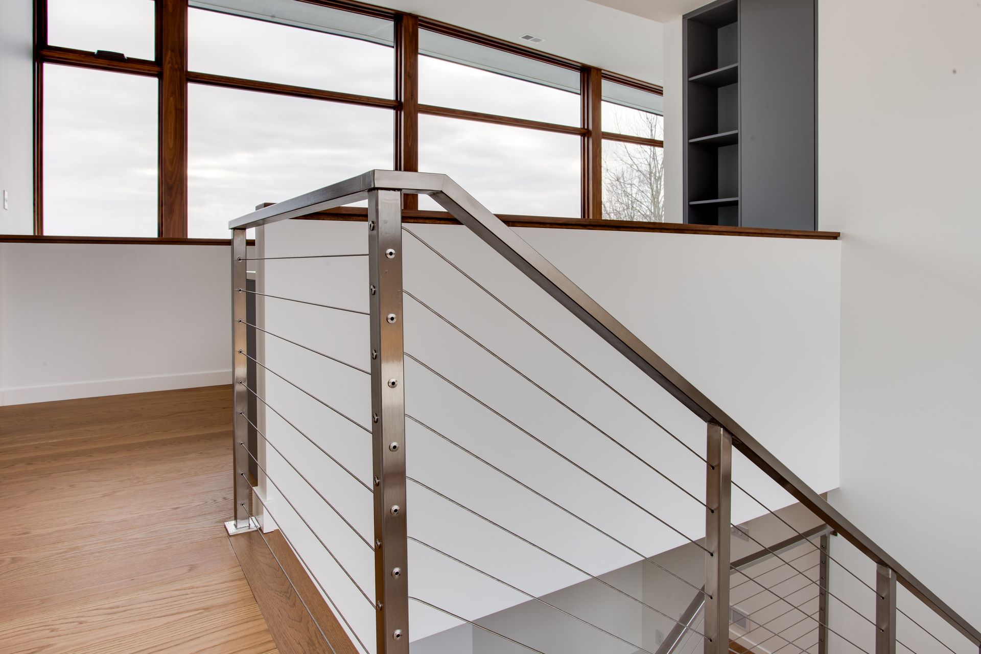 A staircase with a stainless steel railing and a white railing.
