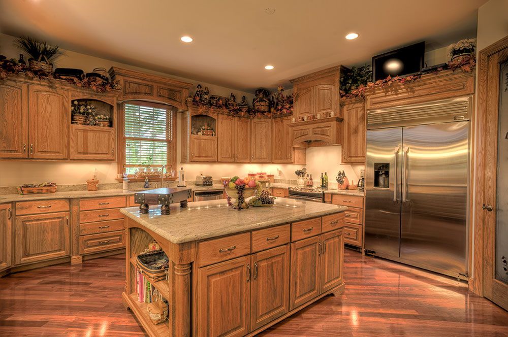 A kitchen with stainless steel appliances, a wooden floor, and wooden cabinets.